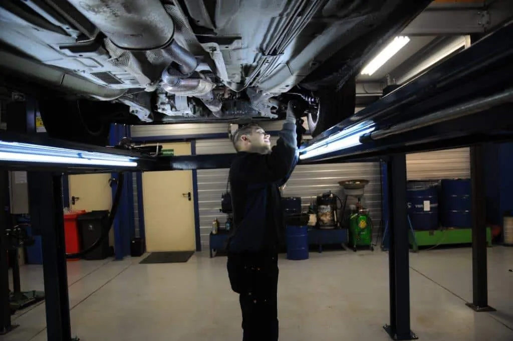 Monteur aan het werk onder een auto op de brug